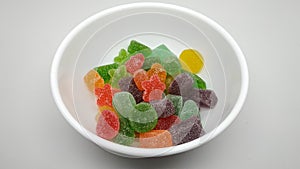 Colorful sweet gummy sugar candy in the white bowl top view