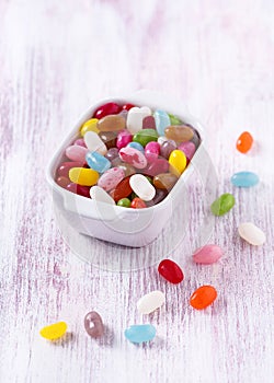 Colorful sweet jelly beans or gummy candies in white ceramic bowl