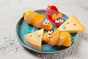 Colourful sweet mini peppers in the shape of mouses and pieces of cheese on a plate, stone table, snack for kids idea