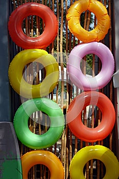 Colorful Swim rings set on bamboo wall. Inflatable rubber toy. Summer vacation or trip safety.