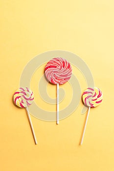 Colorful swirl lollipops on a yellow background. National Candy Day.
