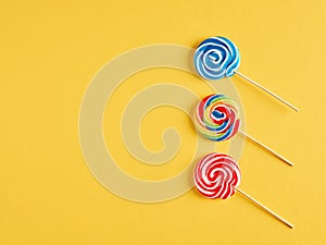 Colorful swirl round candy lollipops on yellow background