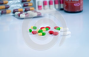 Colorful tablets and capsule pills on blurred background of drug glass bottle and blister pack. Pharmacy drugstore products.