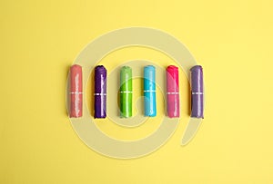 Colorful tampons on yellow background, flat lay