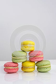 Colorful tasty macaroons rotating on the white background girl flicks the macaroon with finger to the side. Macaroon