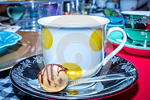 Colorful Tea party with cup of tea in a yellow spotted tea cup and sweet chocolate treat on a tea saucer