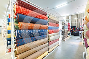 Colorful textile fabric material rolls in warehouse