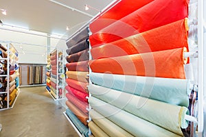 Colorful textile fabric material rolls in warehouse