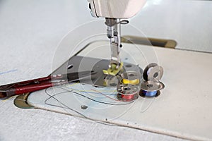 Colorful thread in the bobbins, red yellow blue and white color, with Scissors Clippers put on the Sewing machine.