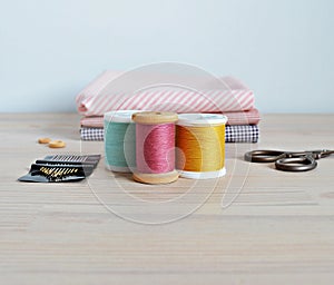 Colorful thread spools , cotton fabrics and quilting needles