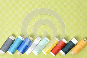 Colorful thread in spools on green background