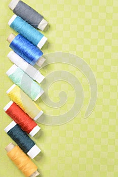 Colorful thread in spools on green background