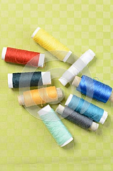 Colorful thread in spools on green background
