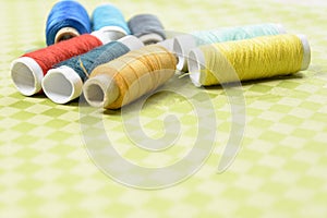 Colorful thread in spools on green background