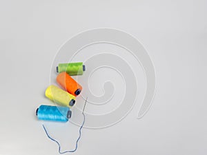 Colorful thread spools and needle on a plain background