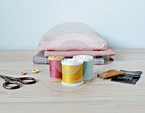 Colorful thread spools , wooden buttons, leather thimble, retro scissors, cotton fabrics and quilting needles