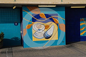 A colorful tile wall mural under florescent lights at Surfers Point at Seaside Park