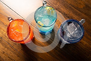 Colorful toned cocktails on wooden background. Frutal alcoholic cocktails. Colorful drinks concept on wooden table