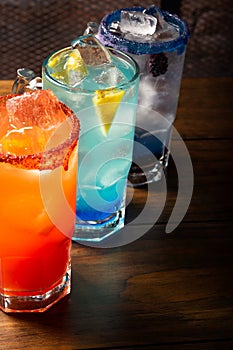 Colorful toned cocktails on wooden background. Frutal alcoholic cocktails. Colorful drinks concept on wooden table