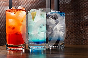 Colorful toned cocktails on wooden background. Frutal alcoholic cocktails. Colorful drinks concept on wooden table.