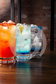 Colorful toned cocktails on wooden background. Frutal alcoholic cocktails. Colorful drinks concept on wooden table