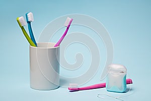 Colorful toothbrushes in mug and dental floss