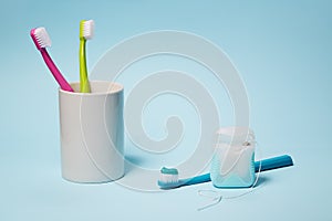 Colorful toothbrushes in mug and dental floss