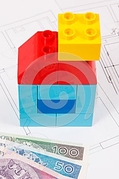 Colorful toy blocks in shape of house, polish currency money and construction housing plan. Buying or renting home concept