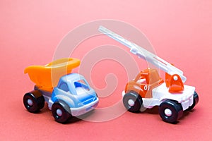 Colorful toy truck and fire truck on a pink background