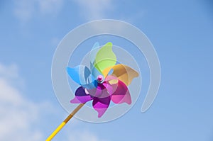 Colorful toy windmill on the background of a bright blue sky. The colors of the rainbow.