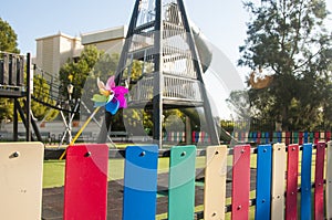 Colorful toy windmill and bright fence on the background of a kidâ€™s playground. The colors of the rainbow.