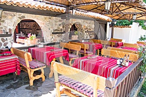 Colorful traditional red tablecloths on wooden tables and benches, old Bulgarian restaurant photo