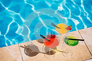 Colorful tropical cocktail with berries on edge of swimming pool