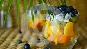 Colorful tropical mix salad in jar. Fresh various kind of raw organic berry and fruit in glass bowl. Healthy vegetarian