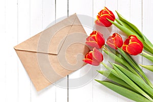 Colorful tulip bouquet and blank greeting card. Top view over white wooden table