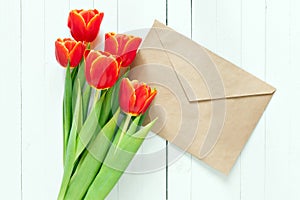 Colorful tulip bouquet and blank greeting card. Top view over white wooden table