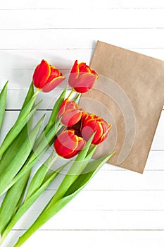 Colorful tulip bouquet and blank greeting card. Top view over white wooden table