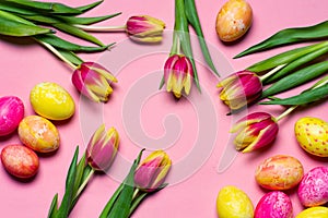 Colorful tulips and painted Easter eggs on pink background