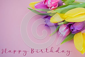 Colorful tulips on soft pink ground with happy birthday ext