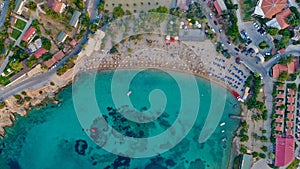Colorful umbrellas on the beach on the shores of Izmir in the Aegean Sea, aerial view of people sunbathing and swimming