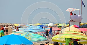 colorful umbrellas on the crowded beach on the sea coast in summ