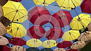 Colorful umbrellas and Edison light bulbs hanging out above a city street