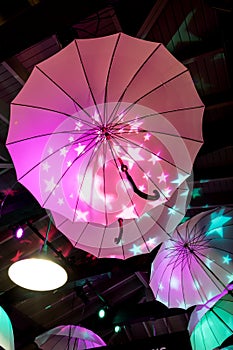 Colorful umbrellas hanging under the ceiling light up with bright stars