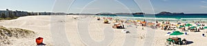 colorful umbrellas and tourists crowd the sand line at Praia do Forte in Cabo Frio, Rio de Janeiro, Brazil