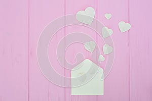 Colorful Valentine Day greeting card envelopes with heart. White hearts pours out of the envelope on pink wooden