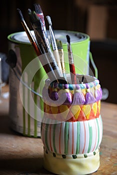 Colorful vase holding artist brushes in a studio setting.