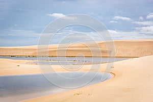 The colorful vast desert landscape of tall, white sand dunes and seasonal rainwater lagoons in a cloudy day at the LenÃ§Ã³is Maran