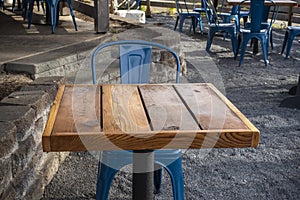 Colorful view of bright blue chairs gathered around a wooden table on an outdoor patio at a restaurant