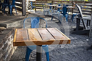 Colorful view of bright blue chairs gathered around a wooden table on an outdoor patio at a restaurant