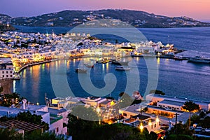 Colorful view after sunset of Mykonos, Greece, harbor and port, ships, whitewashed houses. Town lights up. Vacations